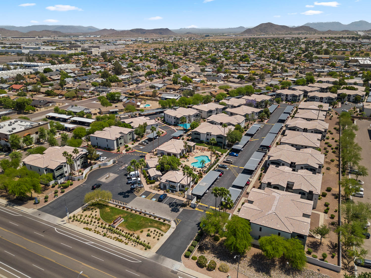Aerial view of property with lots of covered parking and desert landscaping, mountains in the distance