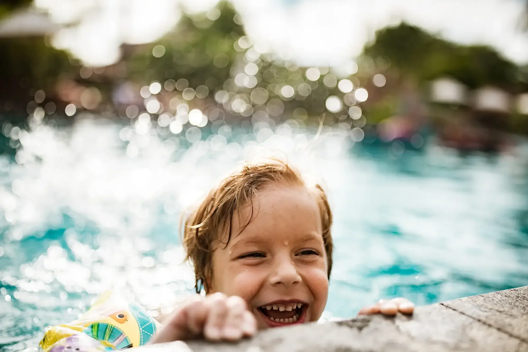 young boy splashing in a pool and laughing