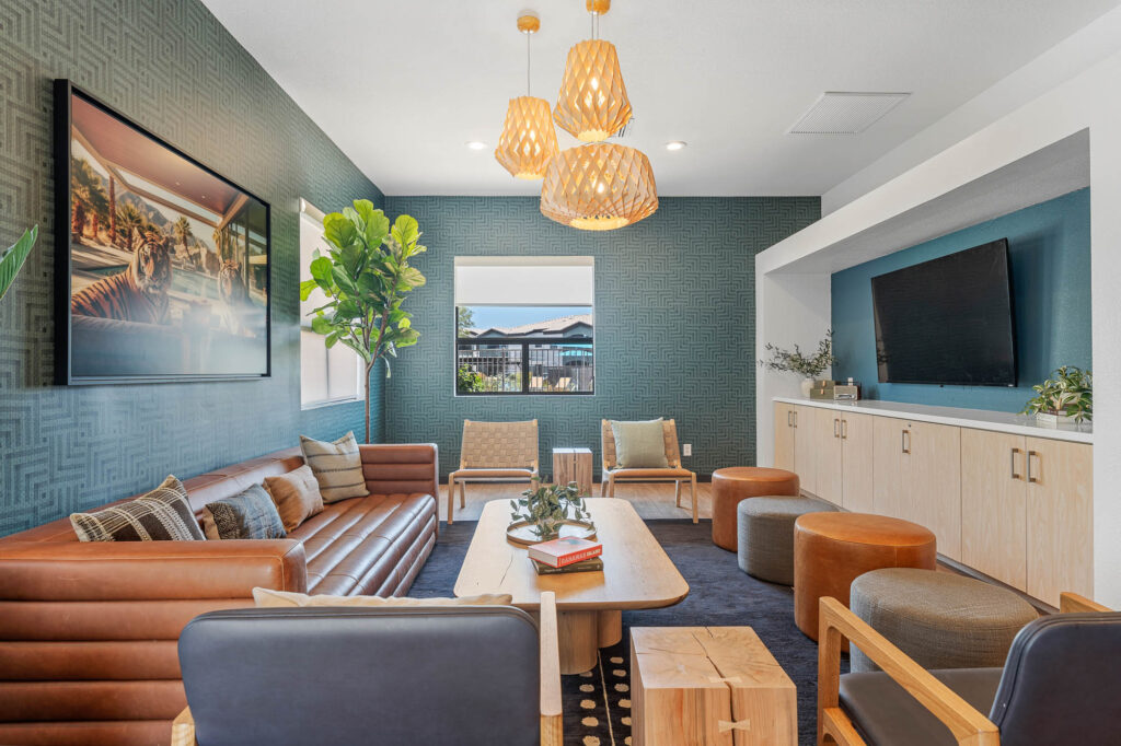 Clubhouse interior with sofa and assorted seating, with paper chandelier, large windows and wall mounted television.